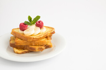 French toasts with banana and raspberry on the white plate on the white background. Copy space.