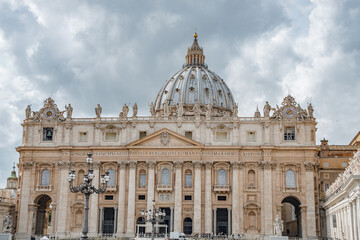 Naklejka premium Dramatic view over Saint Peter Basilica in Vatican city, in the center of Rome, Italy, with heavy clouds.