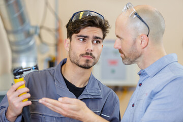 engineer questioning younger worker holding hose