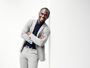 happy african american businessman with arms crossed leaning against white wall