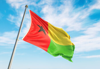 3d rendering Guinea-Bissau flag waving in the wind on flagpole. Perspective wiev Guinea-Bissau flag waving a blue cloudy sky
