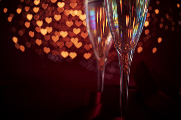 Two champagne glasses in front of romantic red heart bokeh background. Valentine's day celebration background