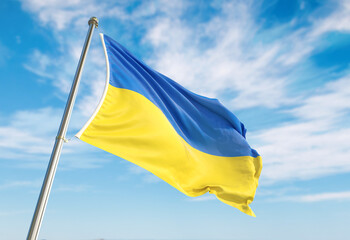 Ukraine flag waving in the wind on flagpole. Ukraine flag waving a blue cloudy sky
