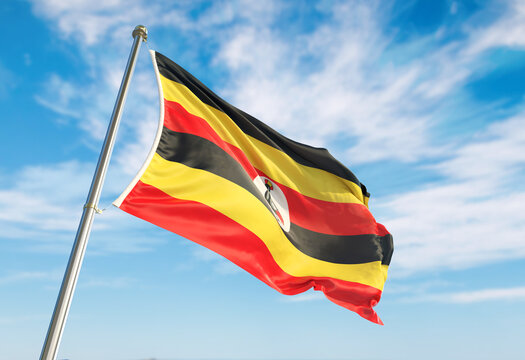 3d rendering Uganda flag waving in the wind on flagpole. Perspective wiev Uganda flag waving a blue cloudy sky