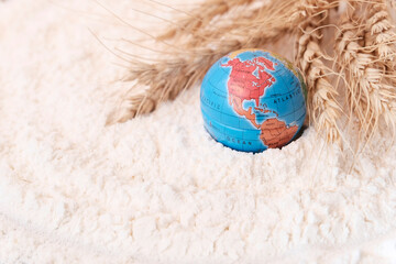 Globe and ears of wheat on a light background, flour texture. The concept of world supply,...