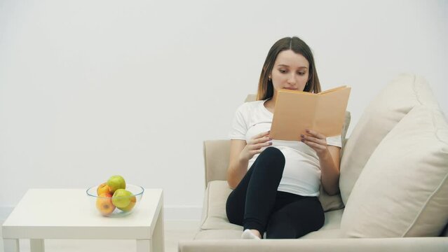 4k video of pregnant woman reading a book.