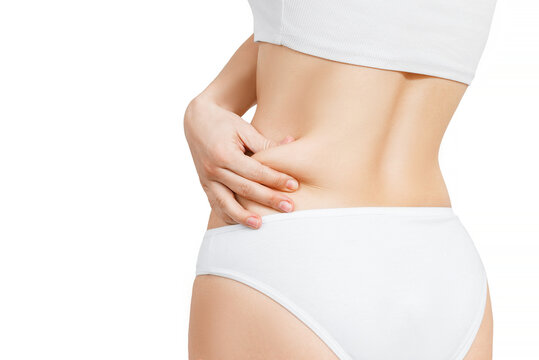 woman in white underwear shows extra fat on the sides of her stomach with her hand. isolate on white background.