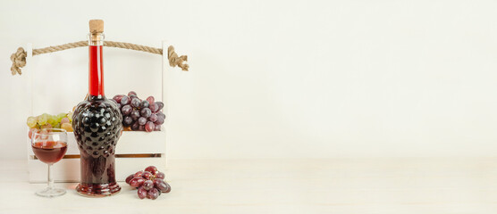 Bottle and glass of red wine on a white wooden background with copy space