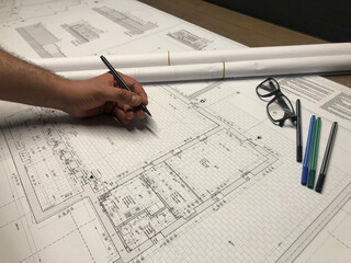 Architectural project design and sketching. Sketch pencils, glasses and male designer hand on map.
