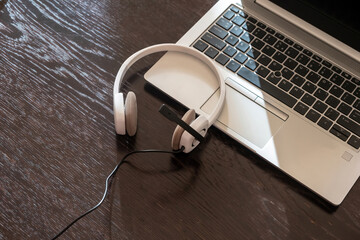 Headset on a laptop, wooden table. Call center, home office, customer support, help desk