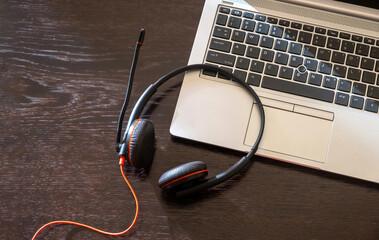 Headset on a laptop, wooden table. Call center, home office, customer support, help desk