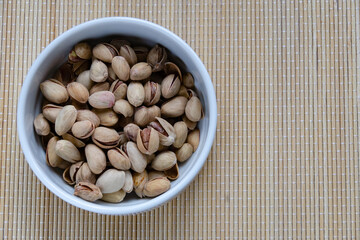 Roasted salted pistachios in a basket, plate on a white background