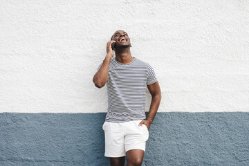 happy african american man in shorts and t-shirt talking with mobile phone