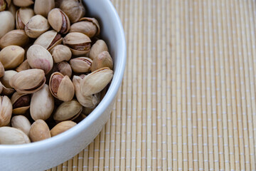Roasted salted pistachios in a basket, plate on a white background