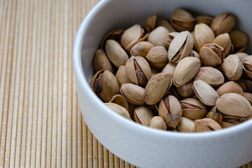 Roasted salted pistachios in a basket, plate on a white background