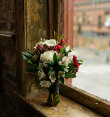 wedding bouquet of flowers sit on a vintage windowsill on elopmenet day