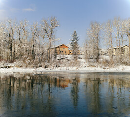 Red building reflects on still icy river