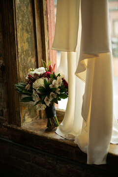 wedding bouquet on a windowsill next to elopement dress