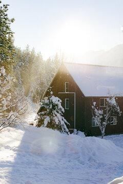 Sunset sets behind a red barn on a sunny snowy day