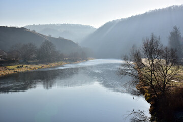Berounka river below the village of Srbsko..River in winter with haze