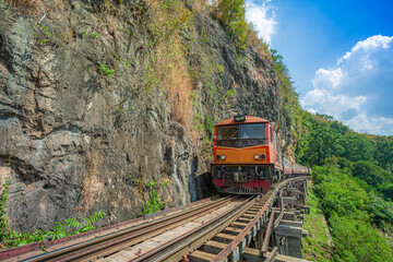 World war II historic railway, known as the Death Railway with a lot of tourists on the train taking photos of beautiful views over Kwai Noi River.