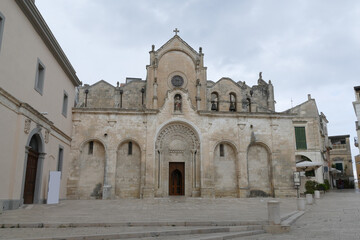 Fototapeta na wymiar Saint Francis church in Matera, the facade in baroque style made by white sandstone with the staircase in front of the entrance door and the decorations.