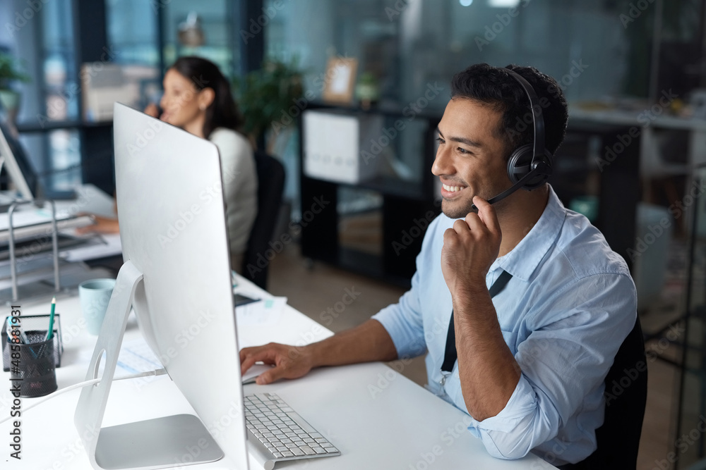 Poster Understanding starts with listening. Shot of a young man using a headset and computer in a modern office.