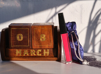 Concept for holiday. International Women's Day. March 8th. Lip gloss, gift and Eternal desktop calendar on a light background with space for text or logo.