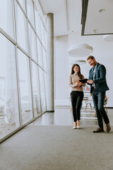 Obraz premium Young entrepreneur couple walking together and using digital tablet in the modern office
