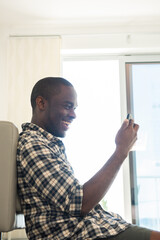 Fototapeta premium happy african american man sitting on floor with mobile phone