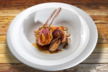 Lamb ribs stuffed with liver baked in the oven with scallions in white plate on wooden table