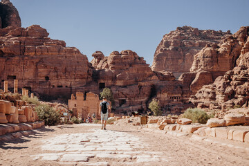 Tourist man with a backpack exploring the sights of the ancient, fabulous city of Petra in Jordan. Colorful photos. Vacation, vacation and travel concept