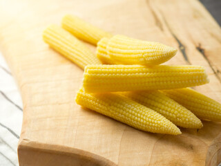 Pickled young corn cobs on a wooden board, milk corn cobs. copy space