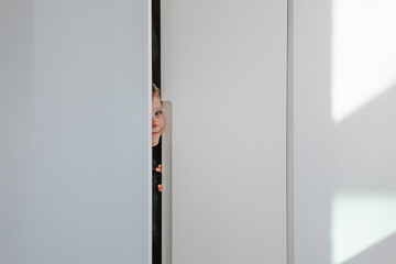 adorable little boy hiding inside a closet playing a game of peek-a-boo