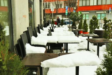 Aftermath of a heavy snowfall, the tables of an outdoor restaurant are covered with a thick layer of snow 
