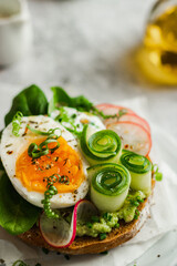 Healthy, natural summer food. Serving of sandwiches with whole grain bread, avocado, eggs, radish, cucumber on white board and white background. Lunch or brunch ideas