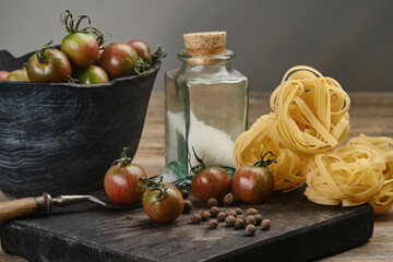 Pasta with tomatoes. Red-green tomatoes with spices and in a black wooden bowl. Selective focus