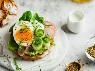 Healthy, natural summer food. Serving of sandwiches with whole grain bread, avocado, eggs, radish, cucumber on white board and white background. Lunch or brunch ideas