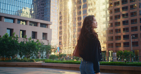 Fototapeta na wymiar Asian woman going street back view. Lady look around high urban buildings.