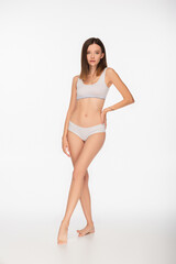 Obraz premium full length view of young and slim woman in lingerie standing with hand on hip on white background