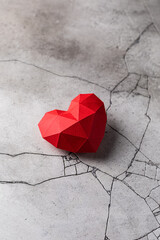 Red paper heart isolated on grey cracked concrete background