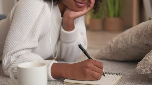 Diary planning. Journal handwriting. Personal list. Closeup of smiling serene woman hand creative author writing notes in notebook enjoying home leisure on cozy floor.
