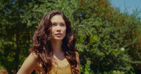 Cute girl posing on green park closeup. Asian woman standing on sunlight outdoor