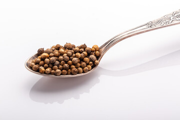 coriander seeds in a cupronickel spoon close up