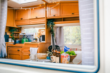Family traveling in camper. Inside house on wheels,trailer,motor home. Dinner table.Food,guitar. Romantic road travel,freedom life.Campsite overnight,van parking.Wanderlust vacation,weekend adventure
