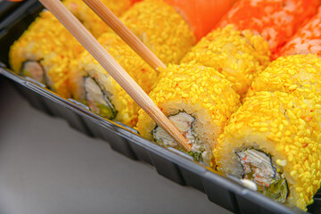 Japanese sushi food, rolls with tuna, shrimp, salmon, crab, avocado, uramaki, hosomaki and nigiri. Assorted different rolls in plastic packaging.