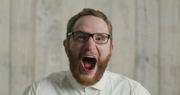 Funny portrait of bearded man screaming at camera.