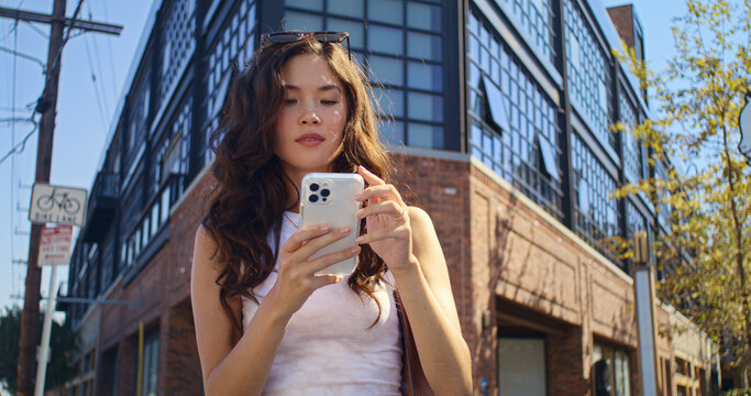 Tourist girl using smartphone on crossroad closeup. Asian woman scrolling phone.