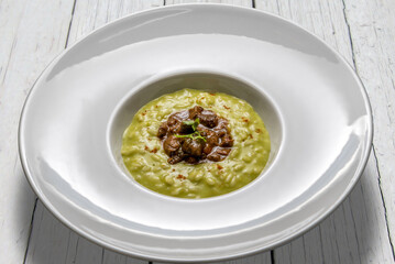 Vegetable risotto with duck stew, in a white plate on white wooden tables