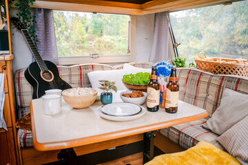 Family traveling in camper. Inside house on wheels,trailer,motor home. Dinner table.Food,guitar. Romantic road travel,freedom life.Campsite overnight,van parking.Wanderlust vacation,weekend adventure